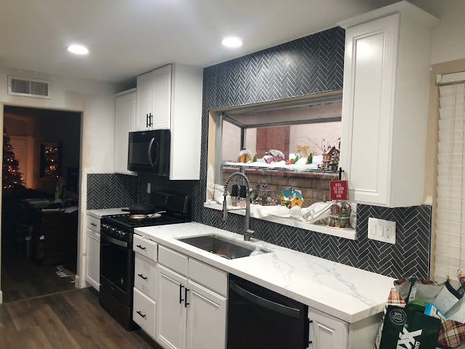 A kitchen with white cabinets and black appliances