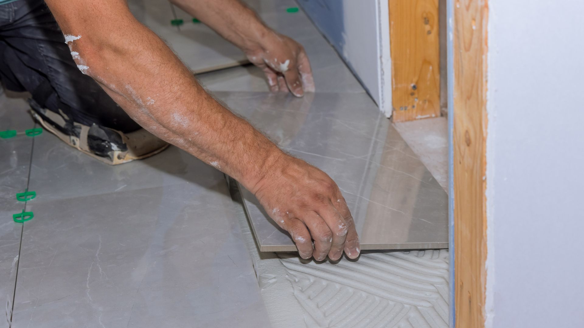 A man is laying tile on the floor