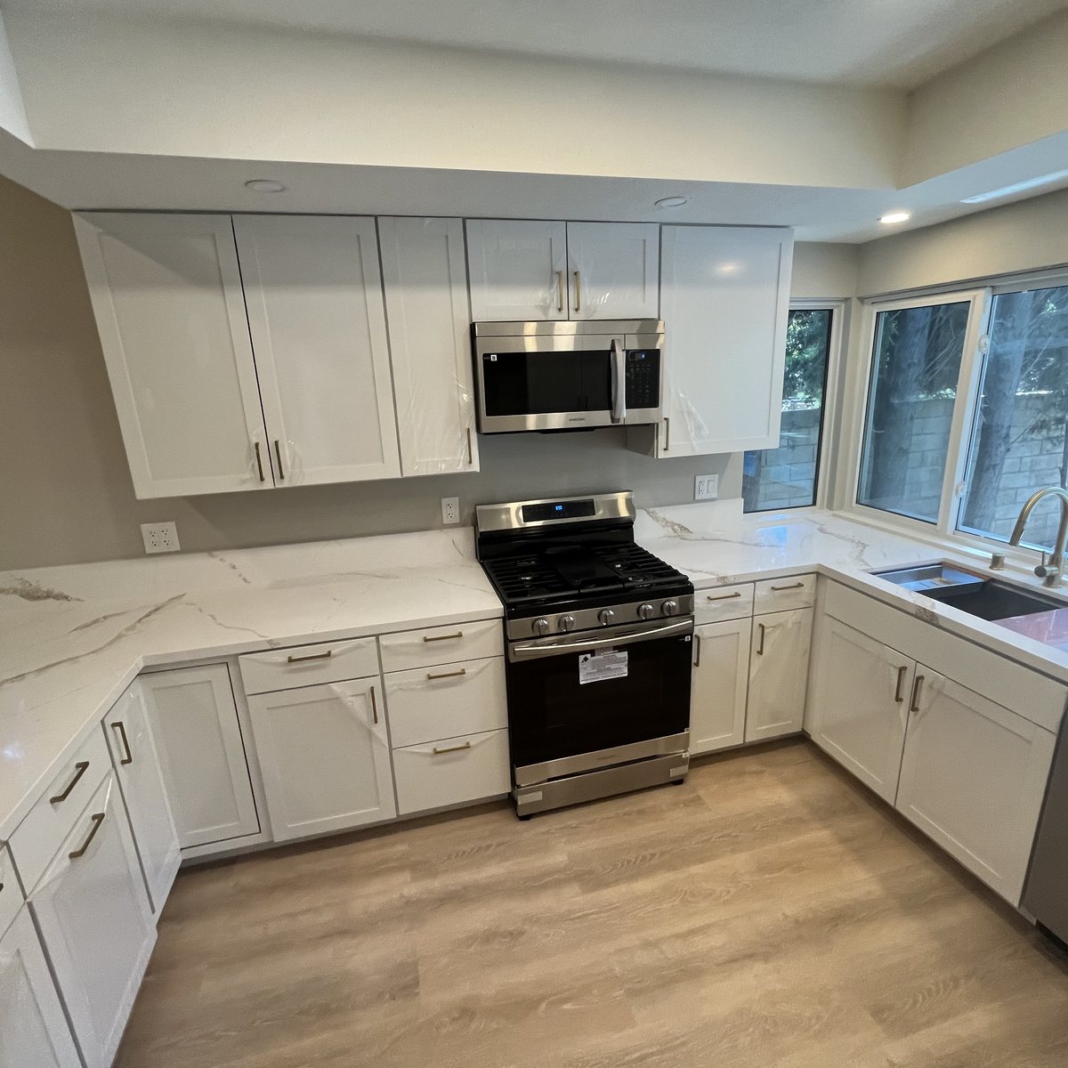 A remodeled kitchen by MG2 Construction with white shaker cabinets, marble-look quartz counters and stainless appliances